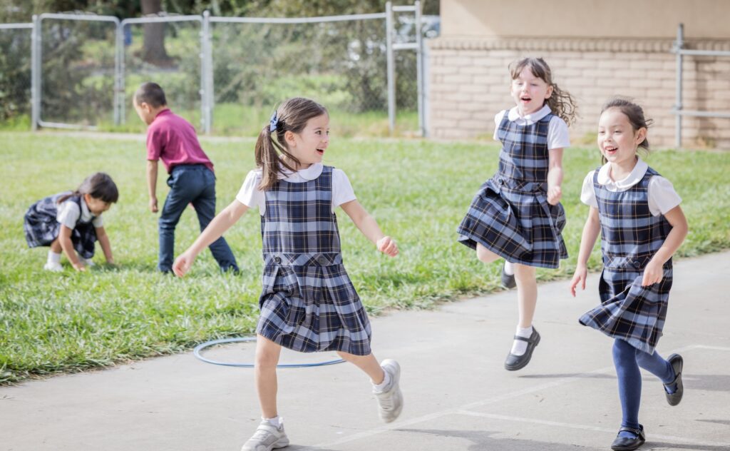 Three Kindergarten girls skip happily at recess.