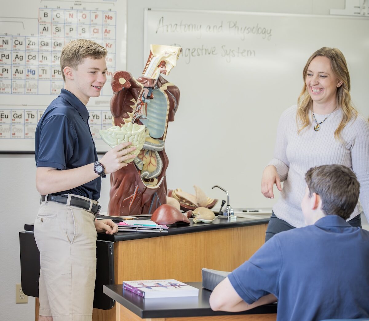 A high schooler holds up a model of an organ during Physiology and Anatomy in the Science Lab.