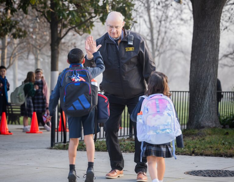 An elementary student jumps to high five the Security guard as students arrive at school at the beginning of the day.