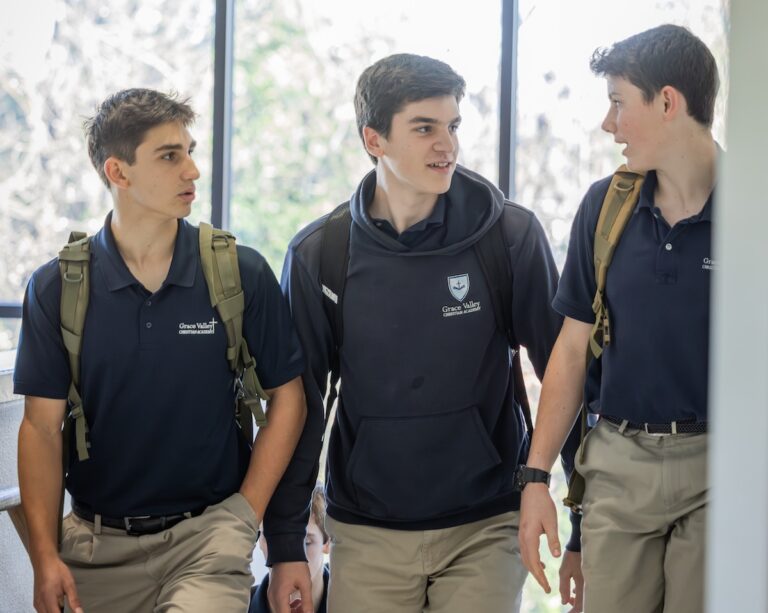 High school boys walk up the stairs to class, engaged in conversation with each other.